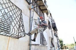 תיקון צנרת חיצונית בבניין בגובה תוך כדי תלייה עם ציוד סנפלינג - "חברת א.א. אברהם שרותי אינסטלציה"